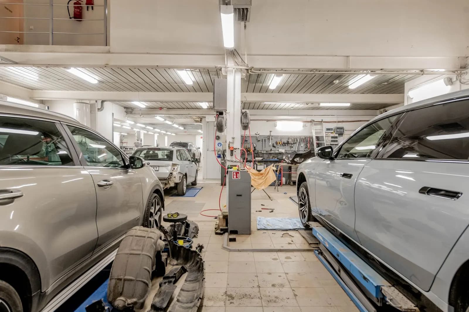 Geniş bir servis holünde kaldırıcılar üzerinde bakım gören araçlar